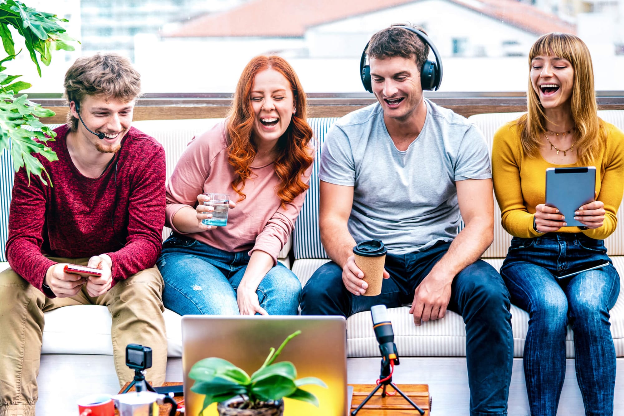 Friends laughing while creating content with a laptop and mic.