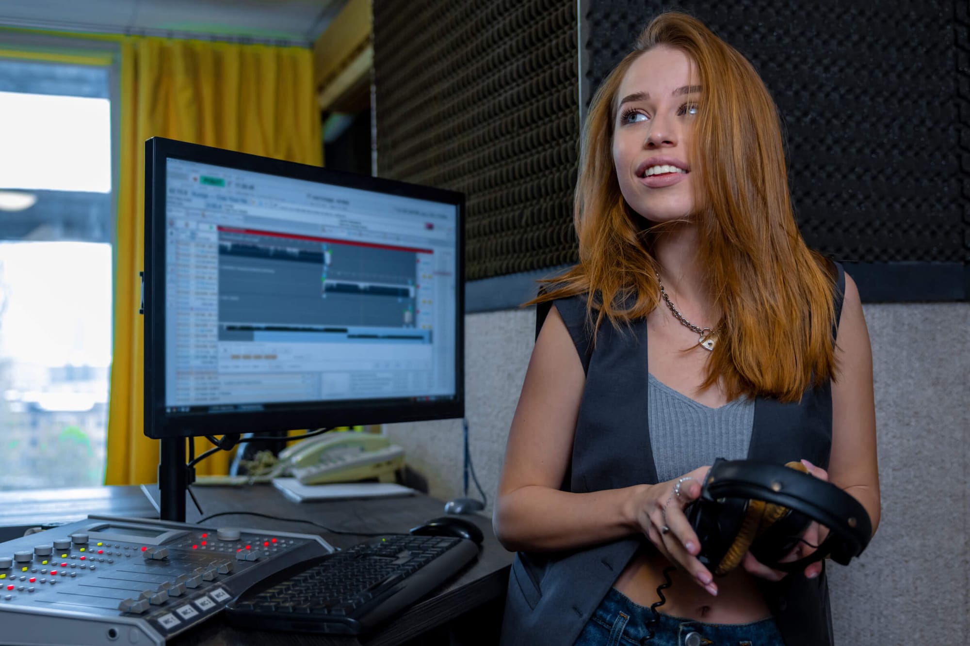 Smiling woman holding headphones in a recording studio