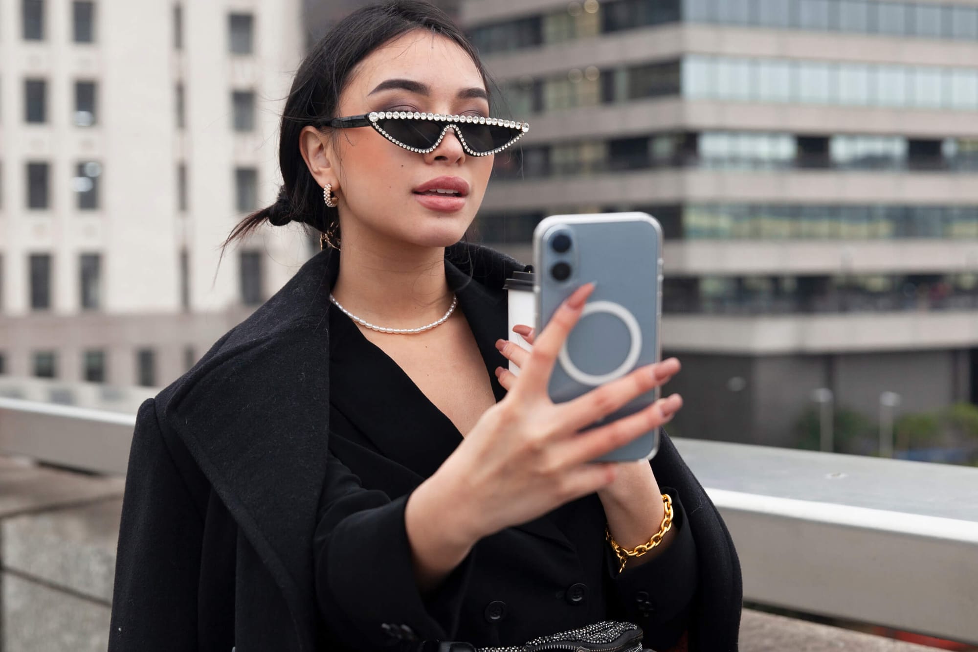 ChatGPT said: Stylish woman wearing pearl sunglasses taking a selfie on a city rooftop.